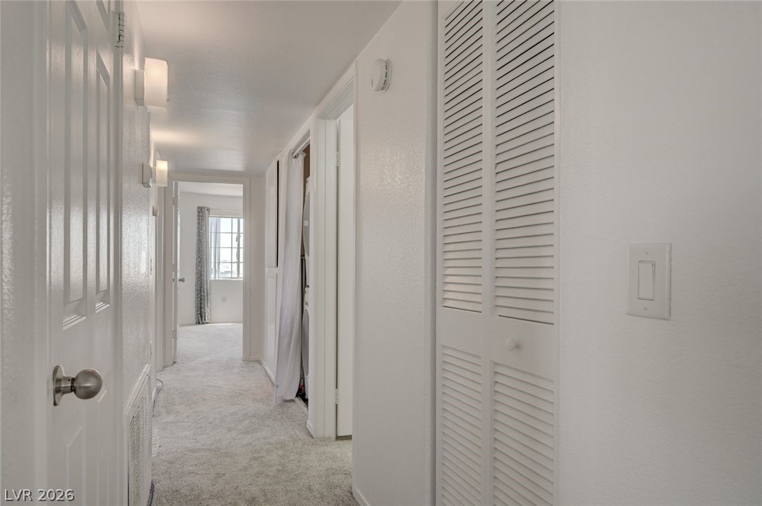 3318 North Decatur Boulevard, Unit 2072 Las Vegas, NV 89130 - Photo 18 of 50 A well-lit corridor with soft carpet flooring provides a path to spacious rooms, perfect for comfortable living.