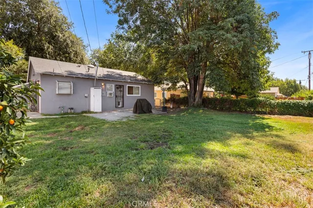 a view of a house with a big yard potted plants and large tree