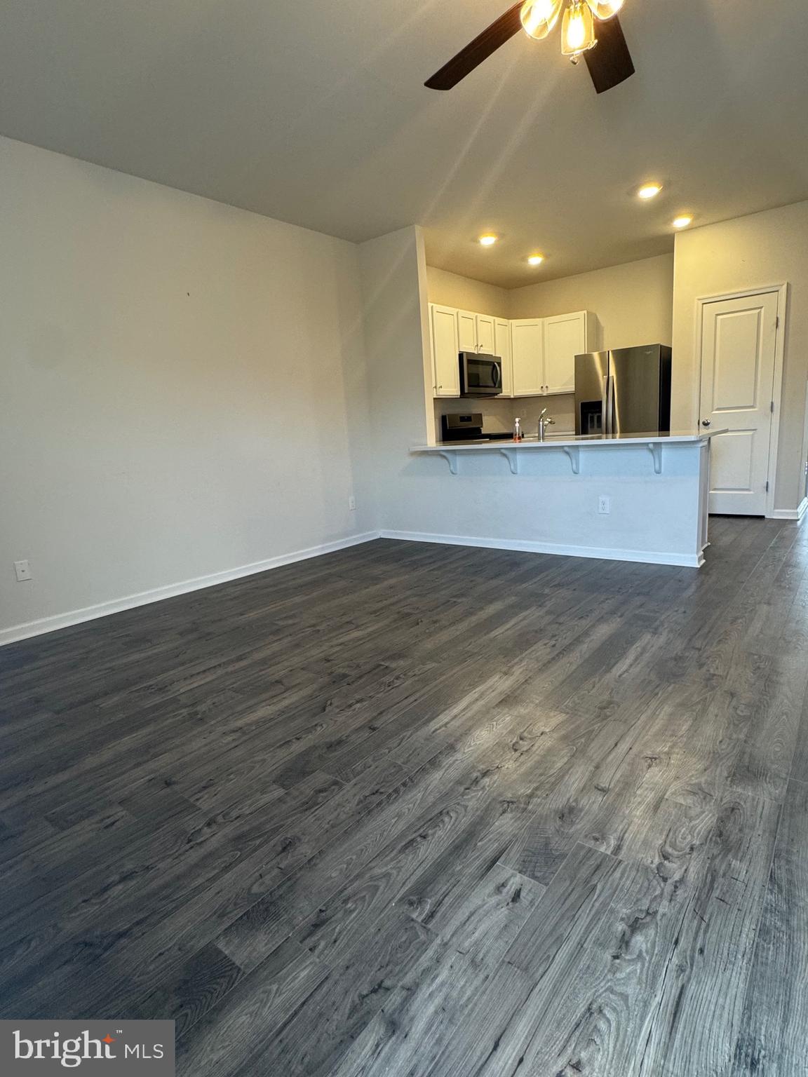 61 Arlotta Street Glassboro, NJ 08028 - Photo 11 of 13 an empty room with wooden floor kitchen view and a chandelier fan