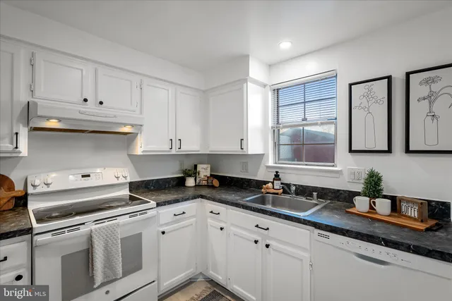 a kitchen with granite countertop white cabinets and stainless steel appliances