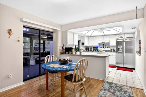 a living room with stainless steel appliances kitchen island granite countertop a table chairs and a living room view
