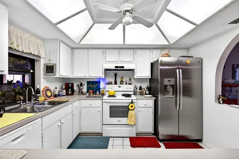 a kitchen with stainless steel appliances granite countertop a refrigerator a sink a stove and white cabinets