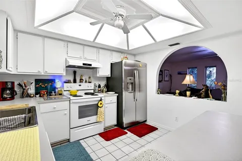 a kitchen with stainless steel appliances kitchen island granite countertop a refrigerator a sink a stove and white cabinets