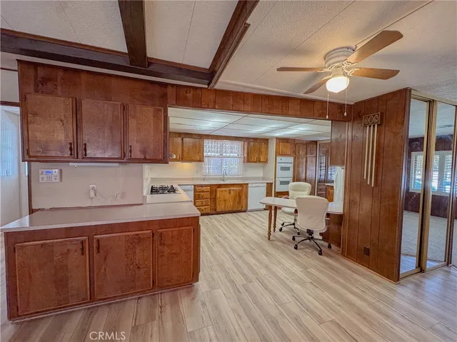 a kitchen with stainless steel appliances granite countertop a refrigerator a sink dishwasher a stove and white countertops with wooden floor