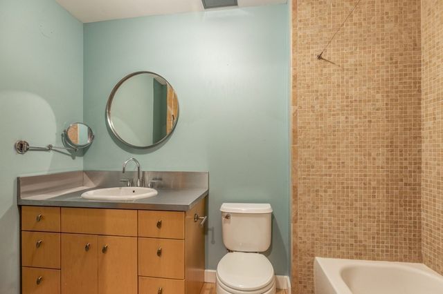 a bathroom with a granite countertop toilet sink mirror and shower