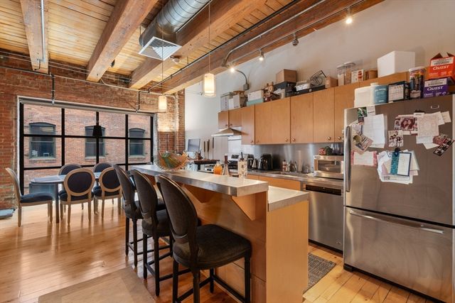 a kitchen with stainless steel appliances granite countertop a stove a refrigerator a dining table and chairs with wooden floor