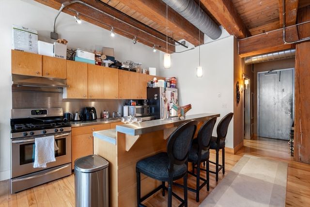a kitchen with stainless steel appliances granite countertop a table chairs sink and cabinets