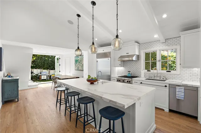 a kitchen with stainless steel appliances a stove a sink a island a stove a table and chairs