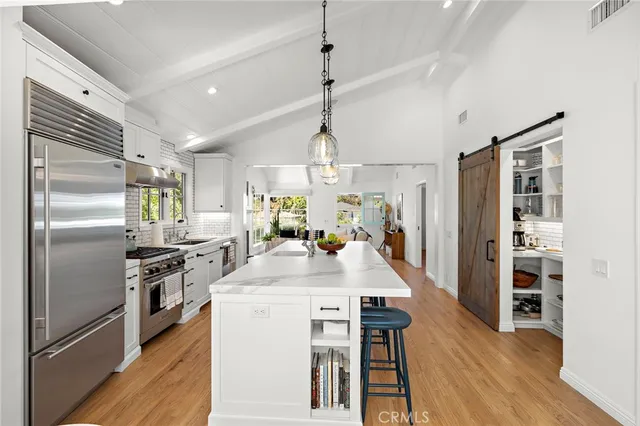 a kitchen with kitchen island a counter top space stainless steel appliances and wooden floor
