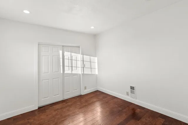an empty room with wooden floor and white walls