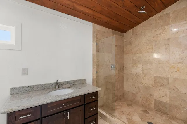 a bathroom with a granite countertop sink a shower and a mirror