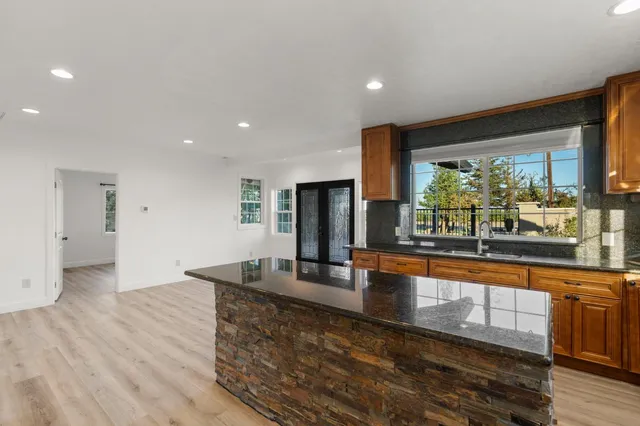 a large kitchen with granite countertop a large counter top stainless steel appliances and a large window