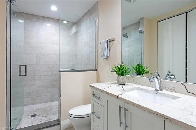 a bathroom with a granite countertop sink a toilet and shower