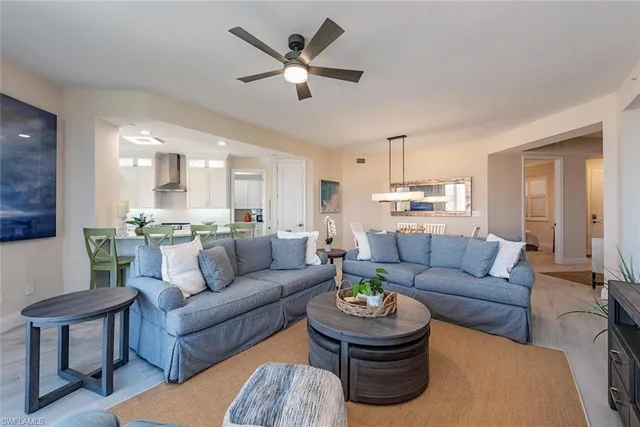 a living room with furniture kitchen view and a chandelier