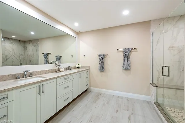 a bathroom with a double vanity sink a mirror and a shower
