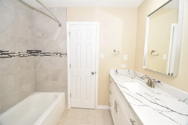 a bathroom with a granite countertop sink a mirror and a bathtub