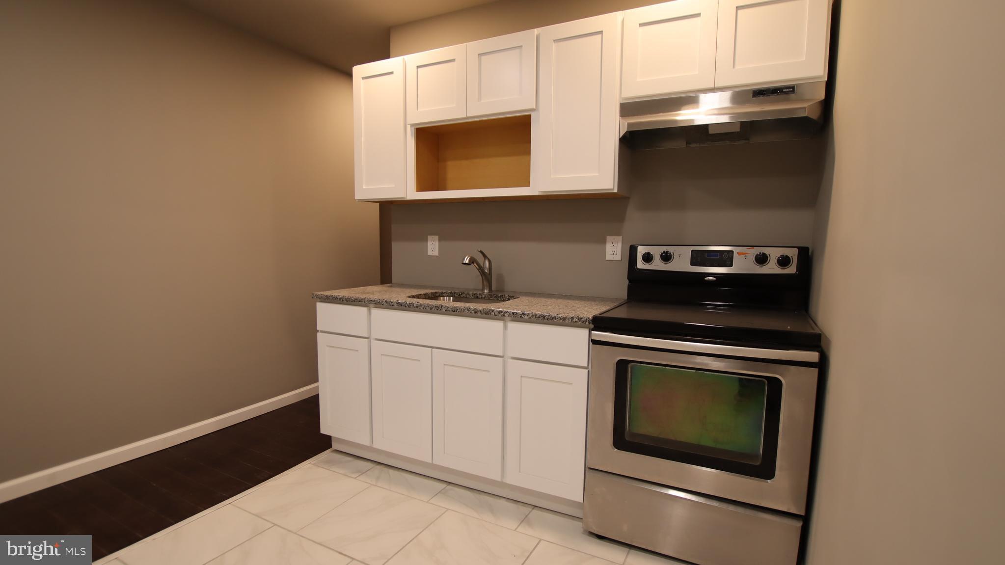 4932 West Thompson Street, Unit 2 Philadelphia, PA 19131 - Photo 6 of 24 a kitchen with granite countertop white cabinets stainless steel appliances and sink