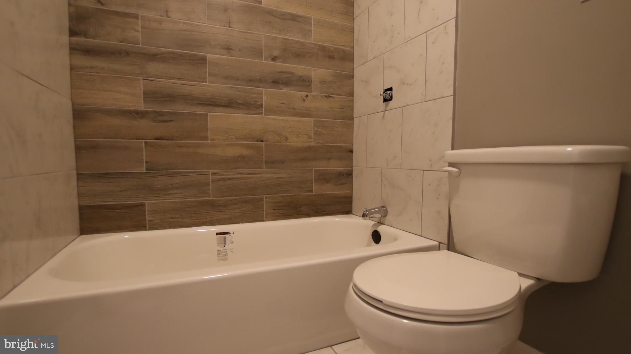 4932 West Thompson Street, Unit 2 Philadelphia, PA 19131 - Photo 9 of 24 a white toilet and tub sitting next to a bathroom sink
