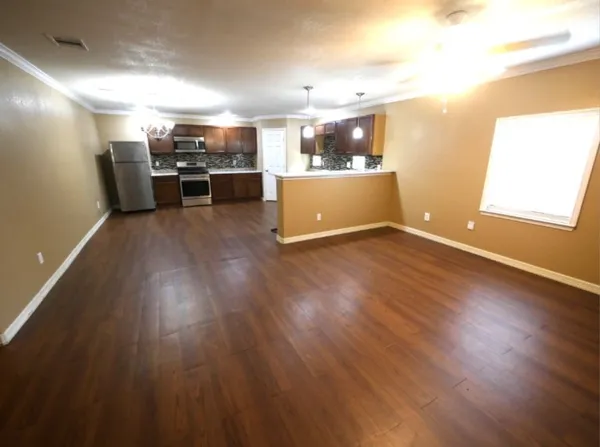 a view of a electric appliances in kitchen and empty room with wooden floor