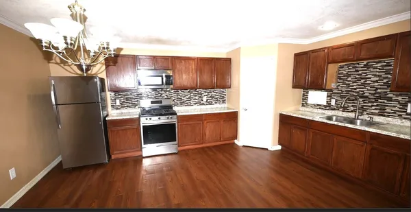 a kitchen with stainless steel appliances a refrigerator a stove a sink cabinets and wooden floor