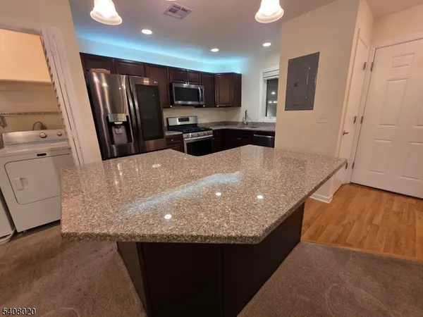 a large kitchen with kitchen island a large counter top space a sink stainless steel appliances and cabinets