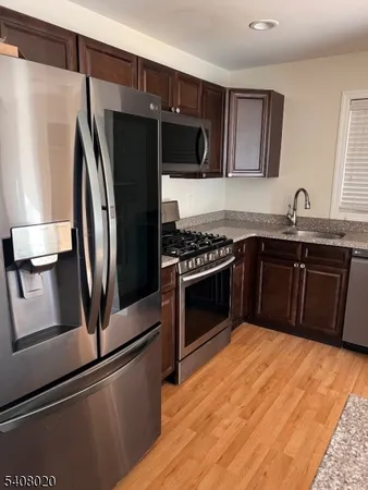 a kitchen with stainless steel appliances granite countertop a refrigerator a sink and a stove