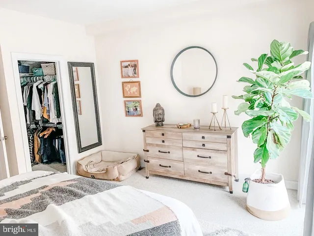 a bedroom with a bed a mirror and potted plant