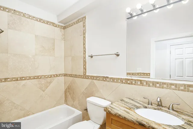 a bathroom with a granite countertop sink mirror vanity and toilet