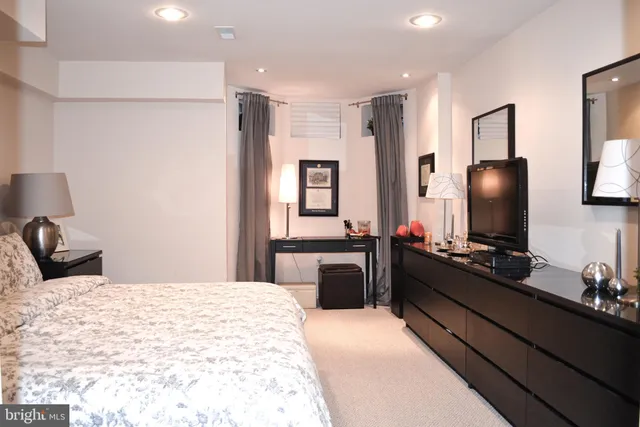 a bedroom with a bed and a flat tv screen on dresser
