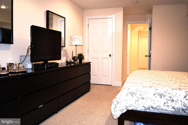 a bedroom with a bed and a flat tv screen on dresser
