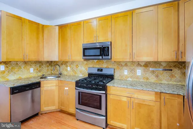 a kitchen with granite countertop wooden cabinets and a stove top oven