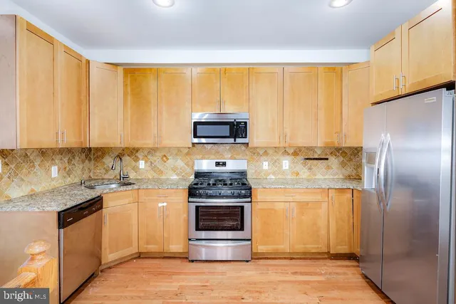 a kitchen with stainless steel appliances granite countertop a stove a refrigerator and a microwave