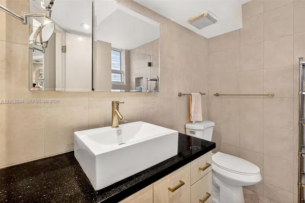a en suite bathroom with a granite countertop sink and a mirror