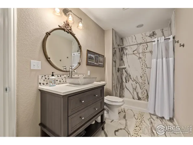a bathroom with a granite countertop sink toilet mirror vanity and shower