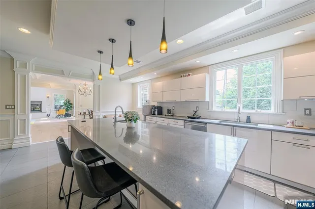 a large kitchen with granite countertop lots of counter space white cabinets and stainless steel appliances