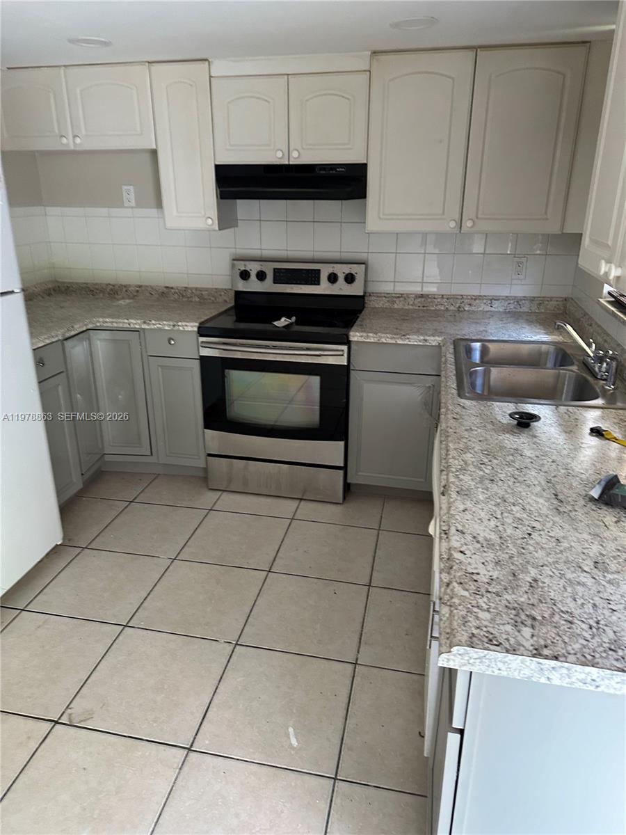 a kitchen with a stove a sink and a counter top space