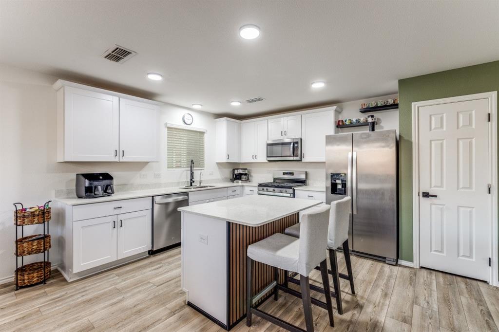 14033 Gaskin Street Pilot Point, TX 76258 - Photo 9 of 12 a kitchen with stainless steel appliances a table chairs refrigerator and a sink
