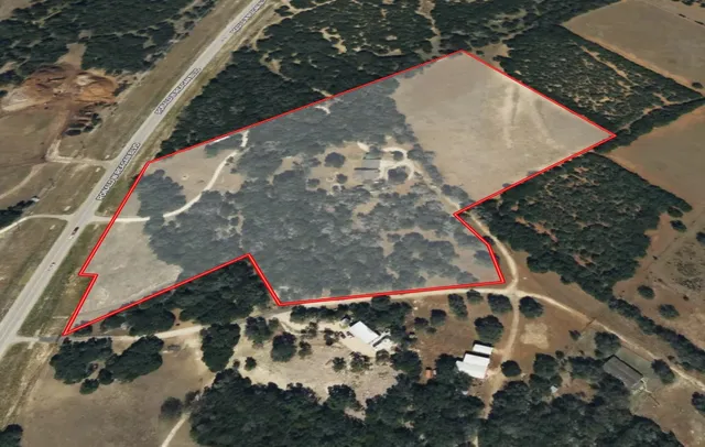 an aerial view of a residential houses with outdoor space and trees
