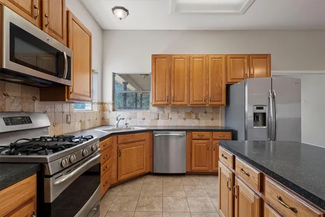 a kitchen with granite countertop stainless steel appliances a sink window and cabinets