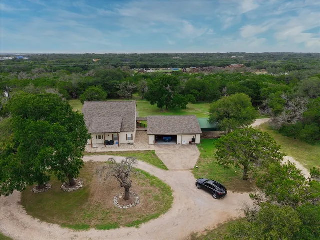 an aerial view of residential house with outdoor space and trees all around