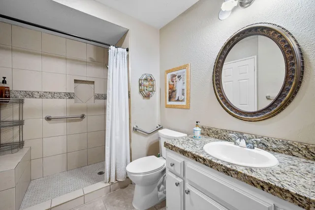 a bathroom with a granite countertop toilet a sink and a mirror