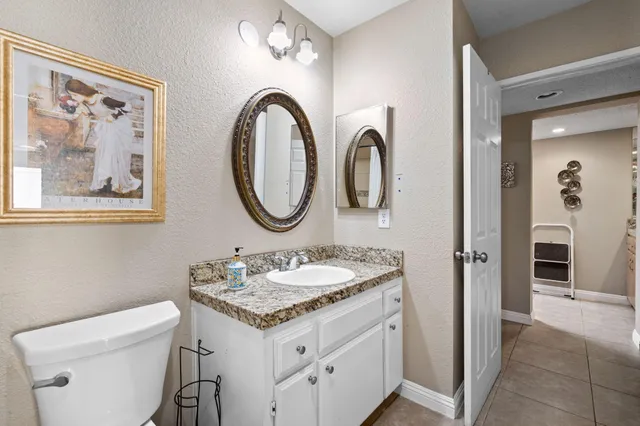 a bathroom with a granite countertop sink a toilet and a mirror