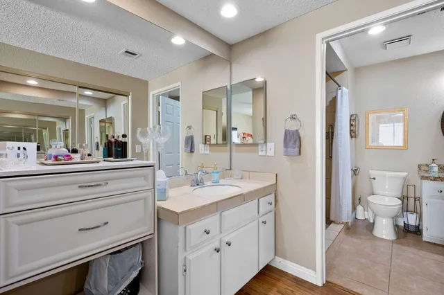a spacious bathroom with a double vanity sink a mirror and a toilet