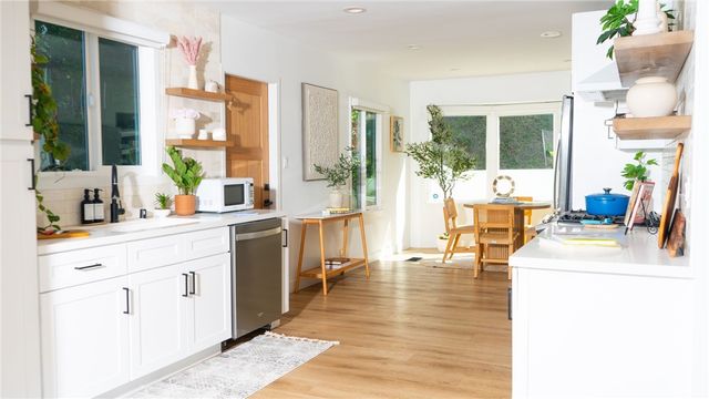 a open kitchen with granite countertop a sink and white cabinets next to a large window