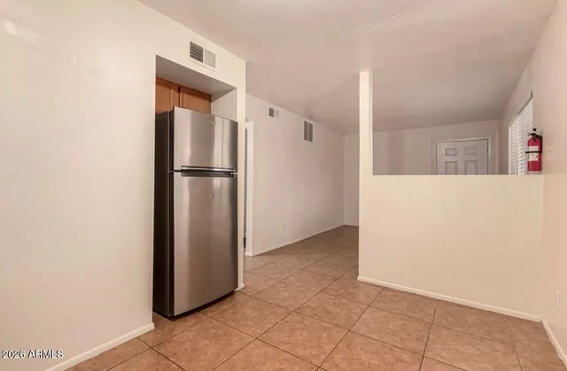 a view of a refrigerator in kitchen and an empty room