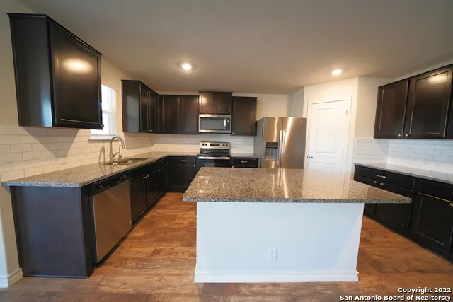 a kitchen with kitchen island granite countertop a sink and stove