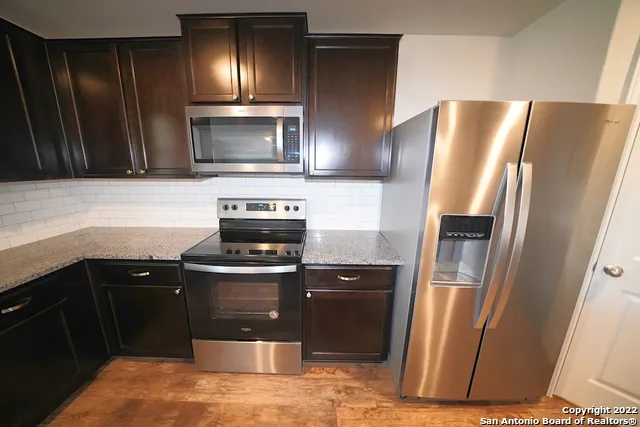 a kitchen with stainless steel appliances granite countertop a refrigerator a stove and a sink