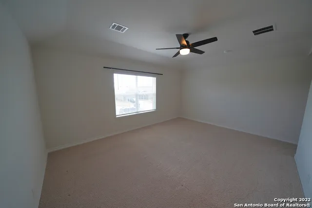 an empty room with windows and fan