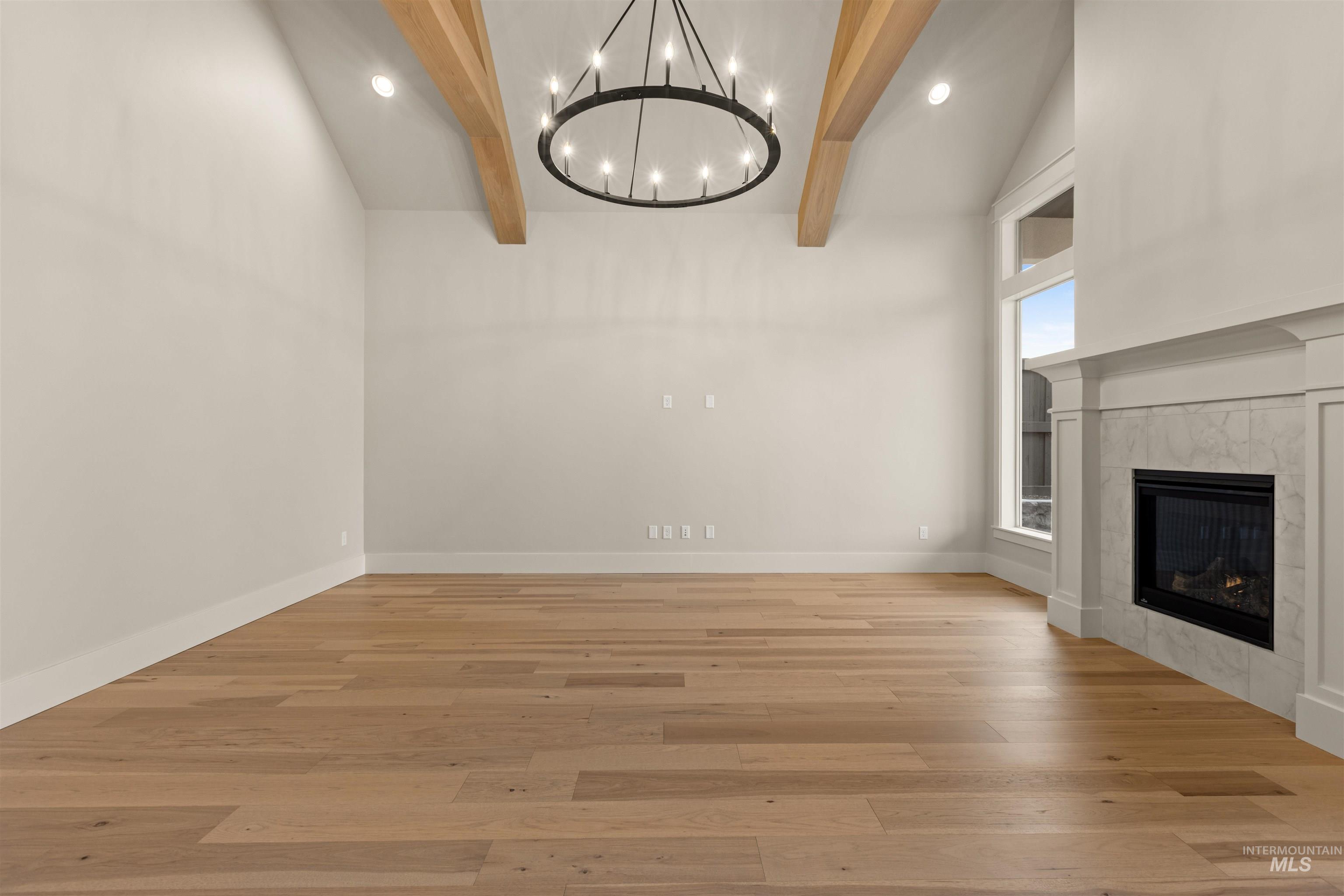6844 South Messner Way Meridian, ID 83642 - Photo 11 of 49 Unfurnished living room with a fireplace, recessed lighting, light wood-style floors, beam ceiling, and a chandelier