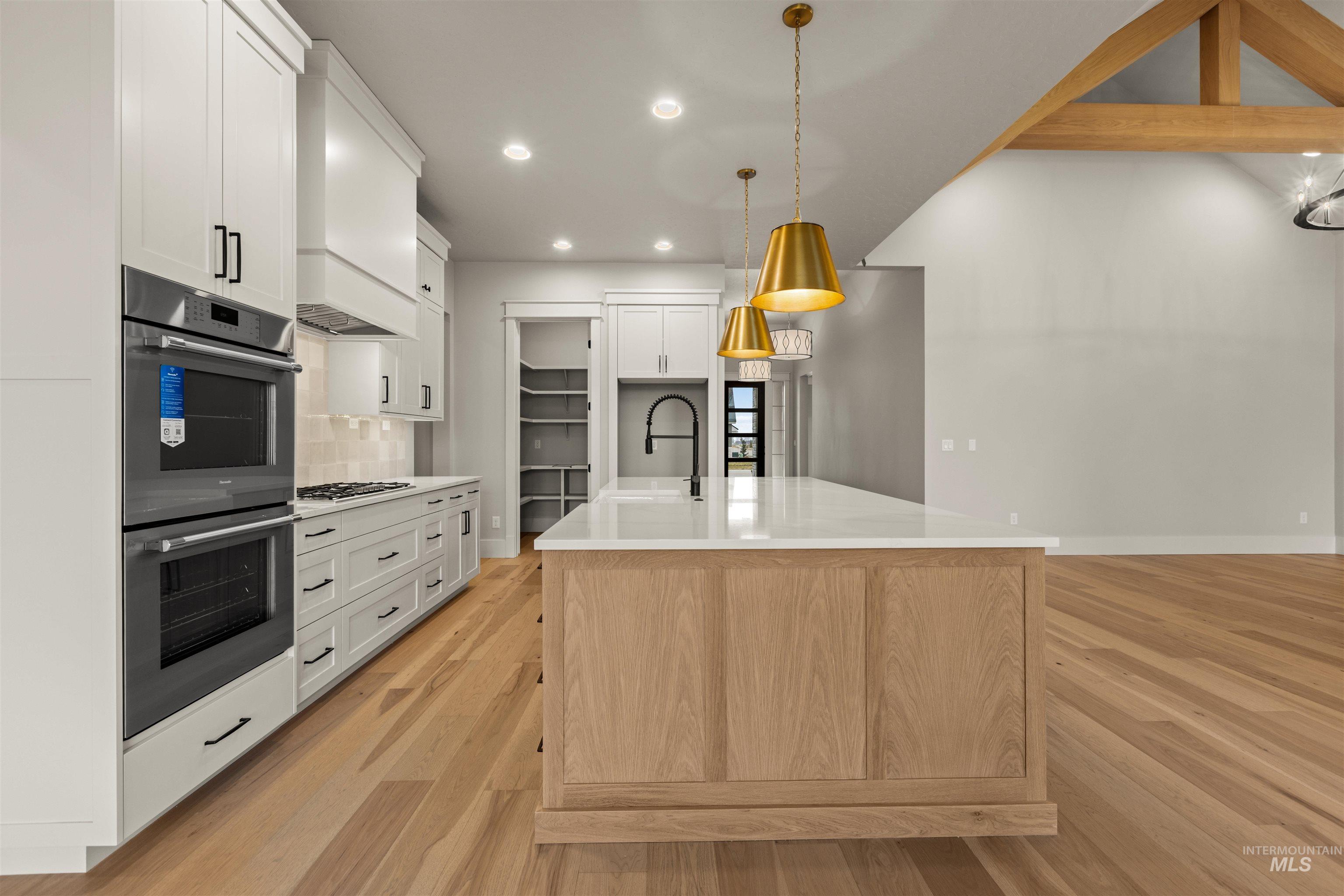 6844 South Messner Way Meridian, ID 83642 - Photo 14 of 49 Kitchen featuring appliances with stainless steel finishes, tasteful backsplash, light wood-type flooring, a kitchen island with sink, and recessed lighting